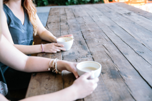 Frauen, die an einem Holztisch Kaffee trinken